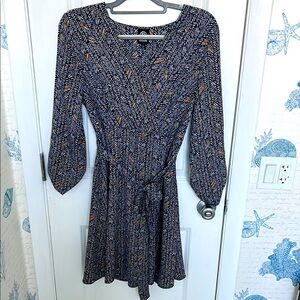 Elegant wrap dress in navy, white, and tan.